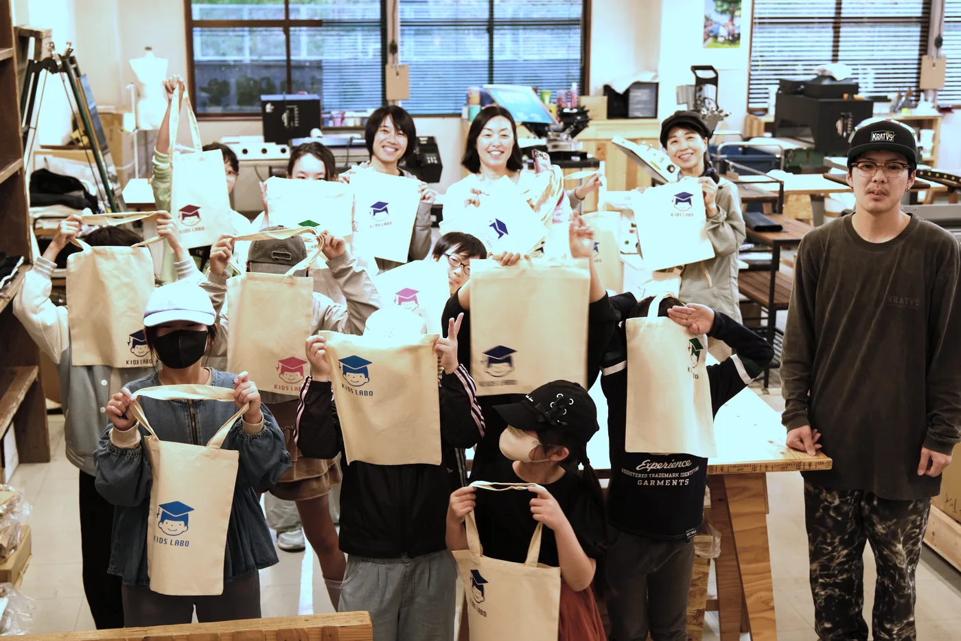 製作したオリジナルトートバッグを掲げるワークショップの参加者
