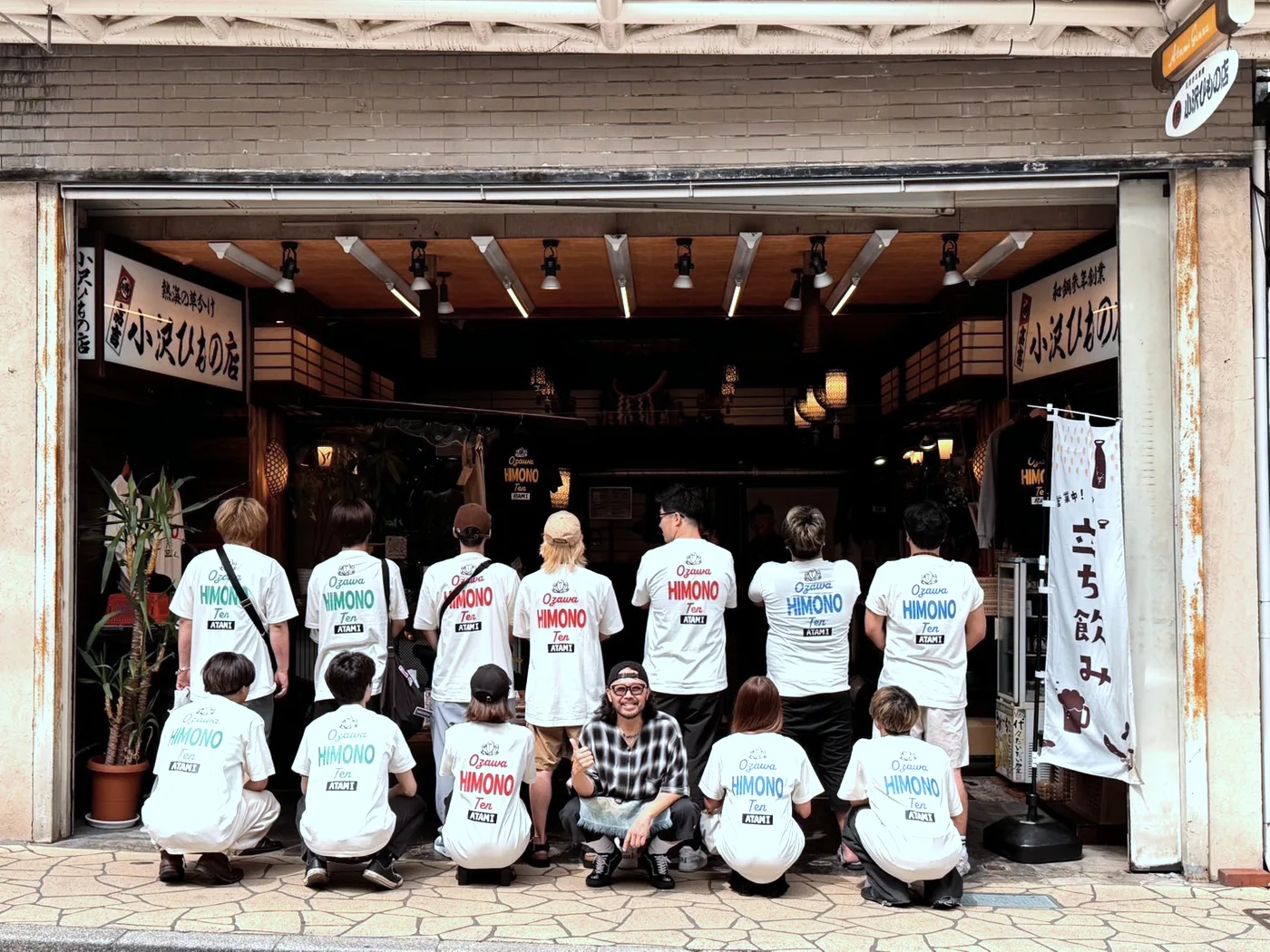 店名入りのオリジナルTシャツを着て店先に並ぶ店舗スタッフ