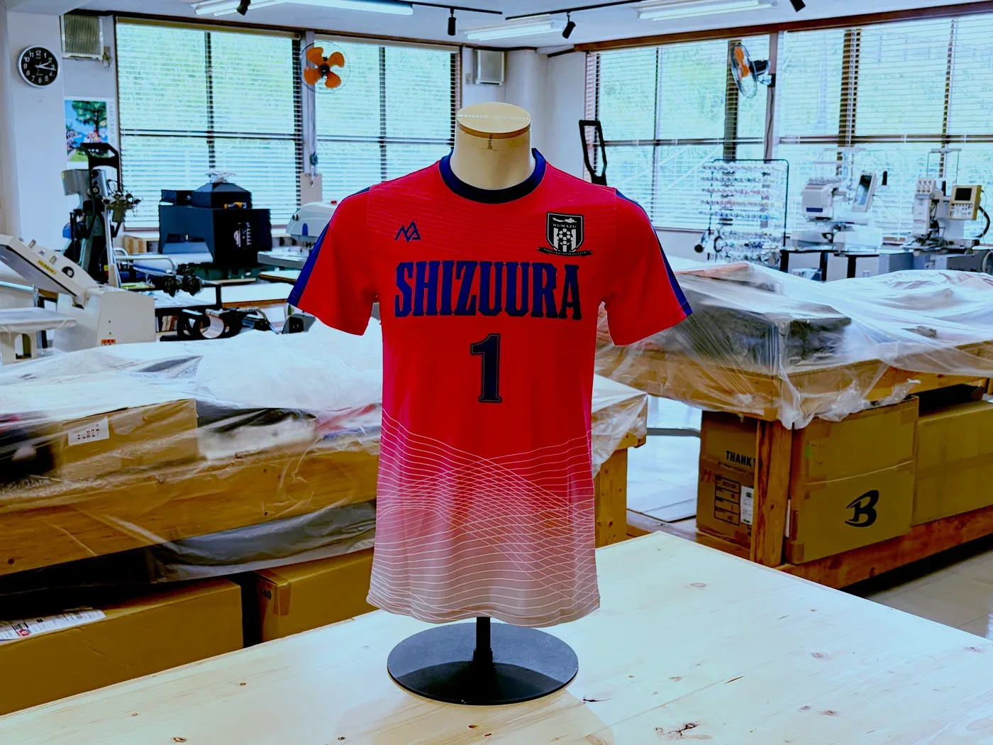 胸にSHIZUURAの文字と背番号1が入った、赤から白へグラデーションする昇華プリントのサッカーユニフォーム